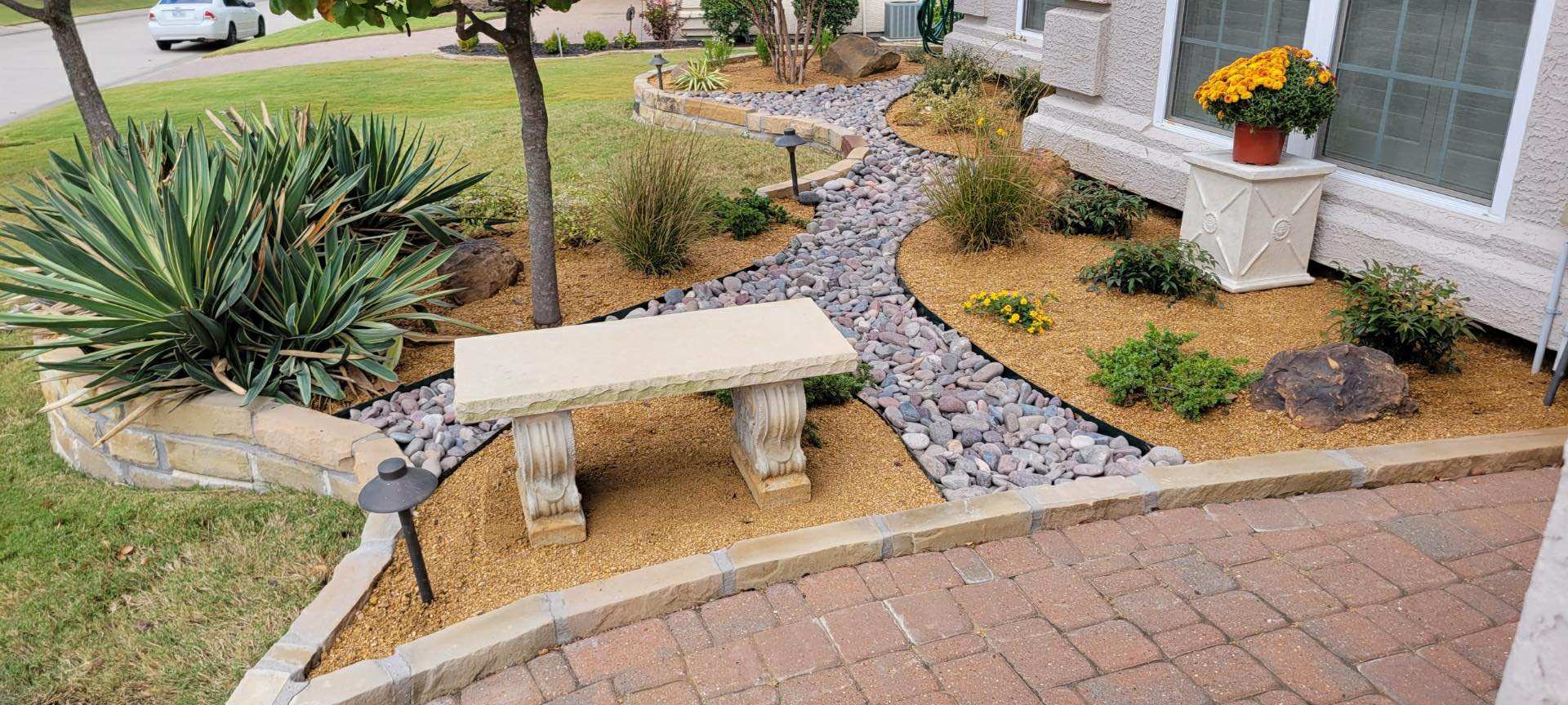 River-rock path with a stone bench, yucca and mixed plantings along a walkway