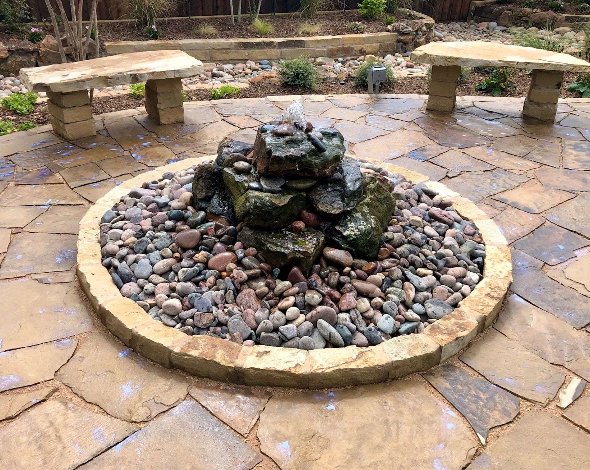 Stone-edged planting bed with decorative gravel and a garden feature