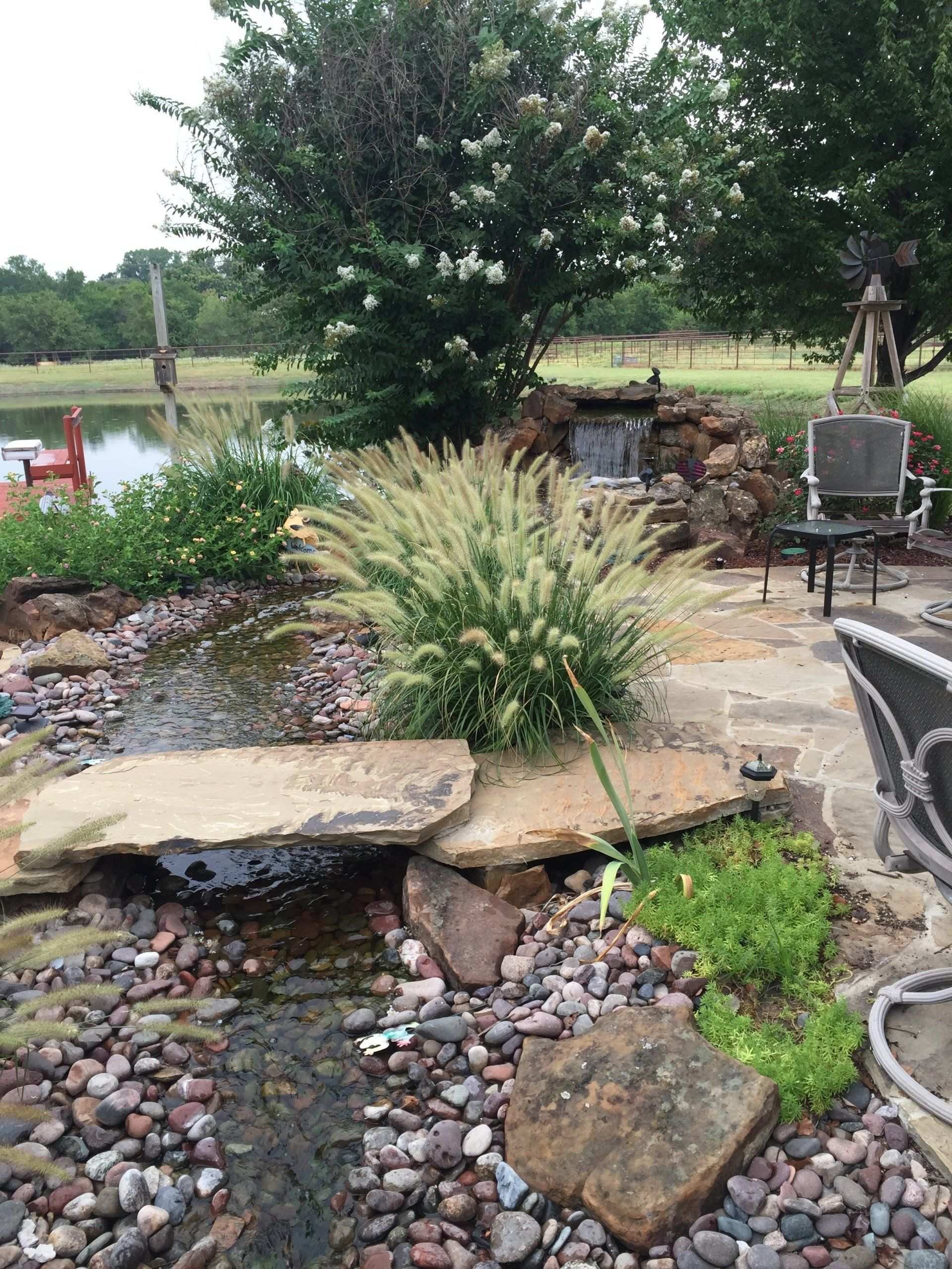 Boulder-edged pond and dry creek bed beside a lakeside patio